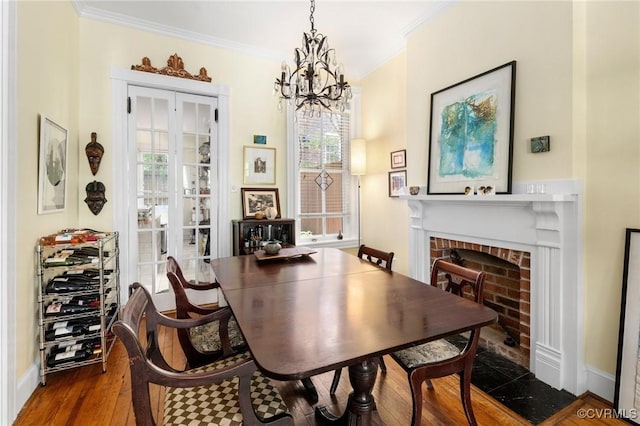 116 N 29th St, Richmond, VA 23223 - dining room featuring ornamental molding, a brick fireplace, wood finished floors, and a chandelier