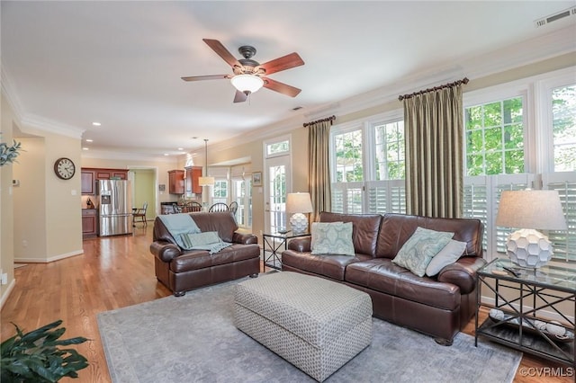 living area with crown molding, a ceiling fan, visible vents, and a healthy amount of sunlight
