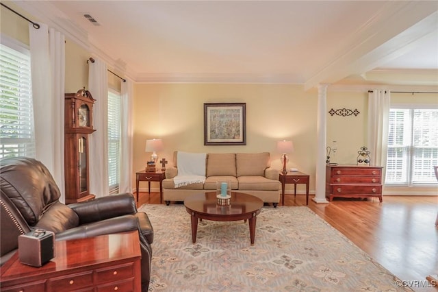 living area with crown molding, ornate columns, wood finished floors, and visible vents