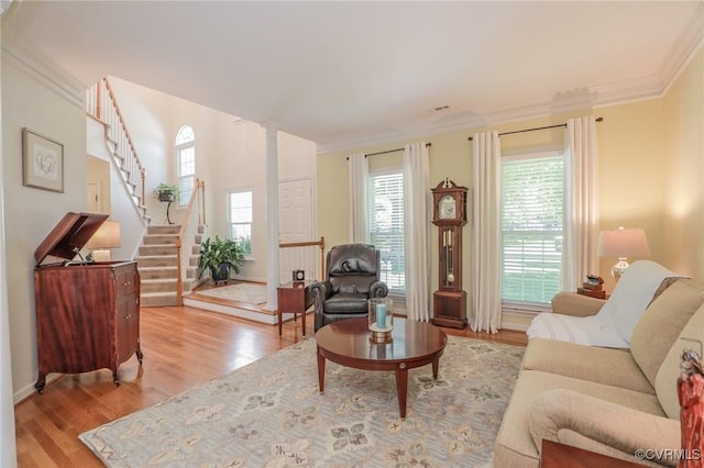 living area with crown molding, a healthy amount of sunlight, stairway, and light wood-type flooring