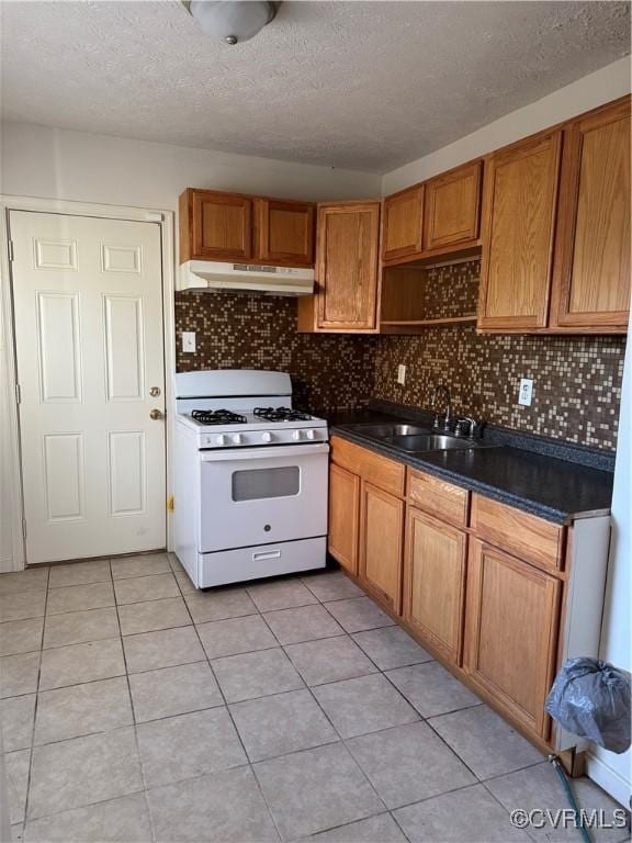2502 Redwood Ave, Richmond, VA 23223 - kitchen featuring a textured ceiling, dark countertops, white range with gas stovetop, under cabinet range hood, and a sink