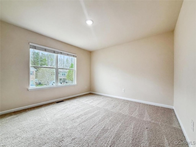 spare room with carpet, visible vents, and baseboards