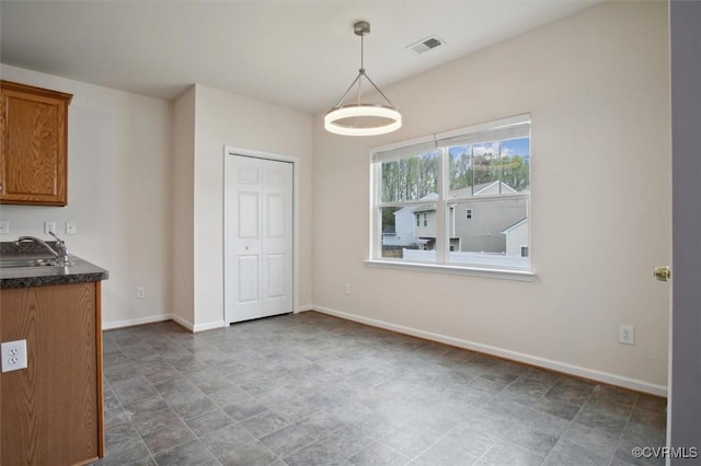 unfurnished dining area featuring baseboards, visible vents, and a sink