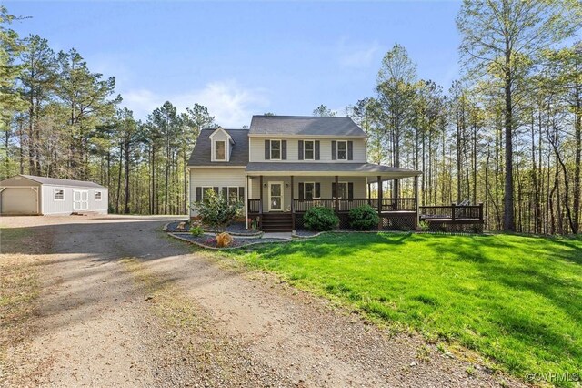 view of front of home featuring dirt driveway, covered porch, an outbuilding, a front yard, and a garage