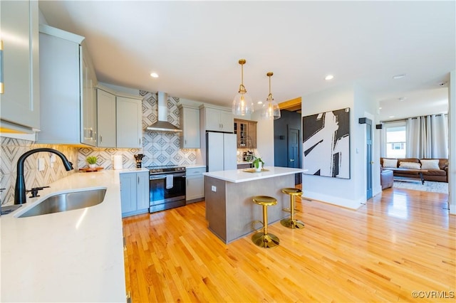 300 W 25th St, Richmond, VA 23225 - kitchen with electric stove, a sink, a breakfast bar, wall chimney exhaust hood, and freestanding refrigerator