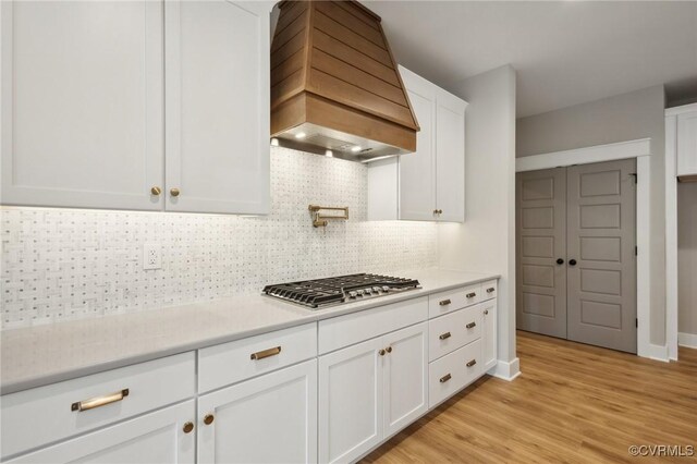 kitchen with premium range hood, decorative backsplash, white cabinetry, and stainless steel gas stovetop