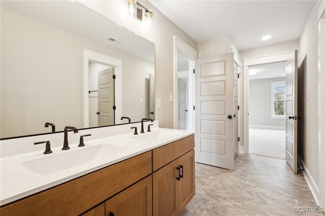 bathroom featuring baseboards, a sink, visible vents, and double vanity