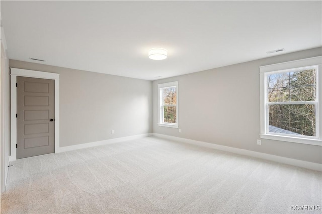 unfurnished room with visible vents, baseboards, and light colored carpet