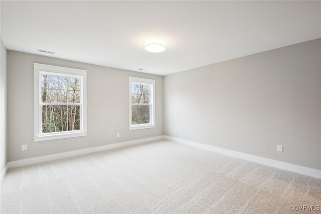spare room with carpet, visible vents, and baseboards