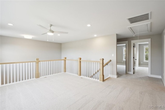 unfurnished room with attic access, baseboards, visible vents, ceiling fan, and carpet floors