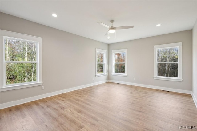 spare room with a wealth of natural light, a ceiling fan, light wood-style floors, and baseboards