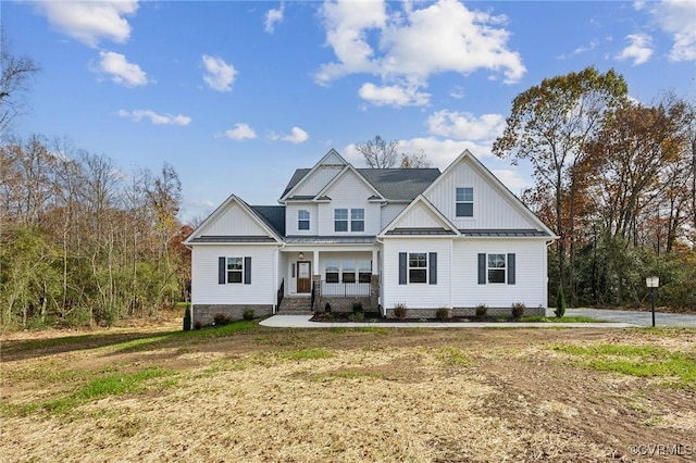 modern inspired farmhouse featuring a front lawn, metal roof, board and batten siding, and covered porch