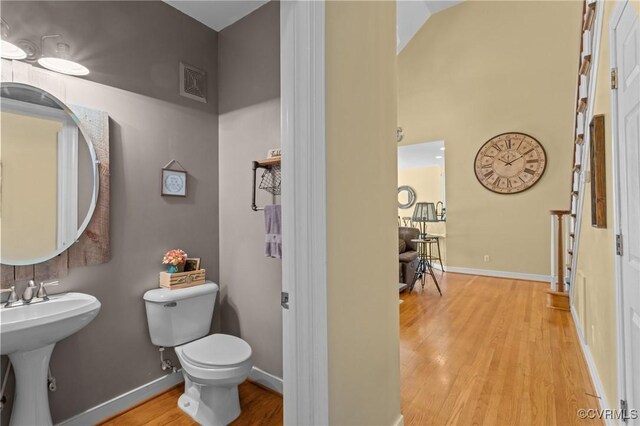 half bath featuring baseboards, toilet, wood finished floors, and visible vents