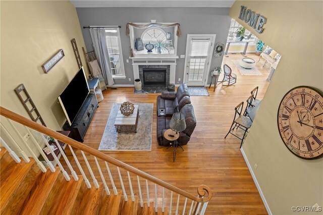living room with baseboards, wood finished floors, stairway, and a high end fireplace