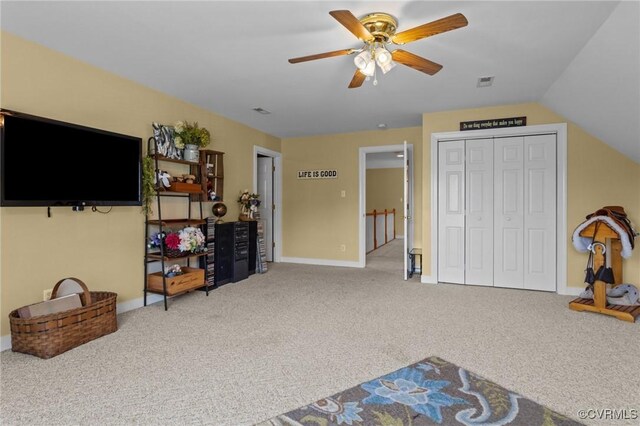 interior space with ceiling fan, visible vents, vaulted ceiling, baseboards, and carpet