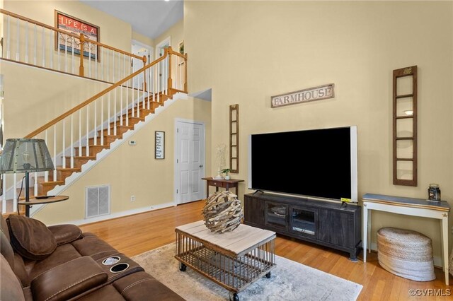 living area featuring stairs, baseboards, visible vents, and wood finished floors