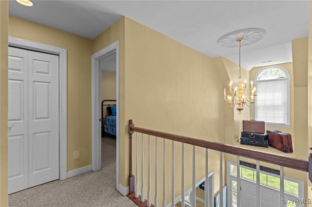 corridor with an inviting chandelier, carpet flooring, baseboards, and an upstairs landing