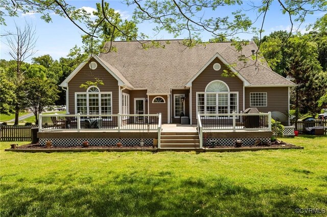 back of house with a lawn, a deck, fence, and roof with shingles