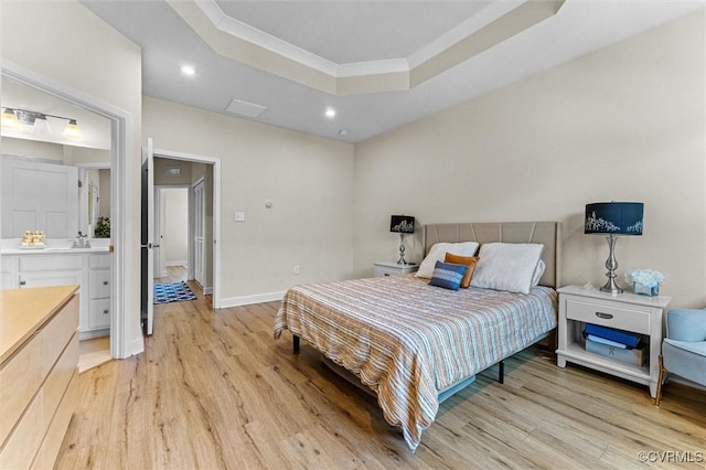 bedroom with a sink, a tray ceiling, light wood finished floors, baseboards, and recessed lighting