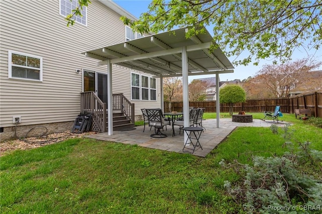 back of house featuring a fenced backyard, a patio area, an outdoor fire pit, and a lawn