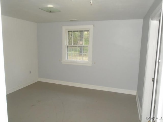 spare room with concrete flooring, visible vents, and baseboards