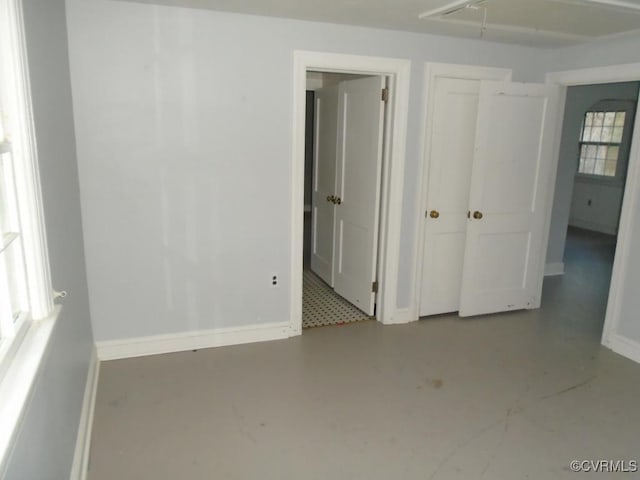 unfurnished bedroom with baseboards, finished concrete floors, and a closet