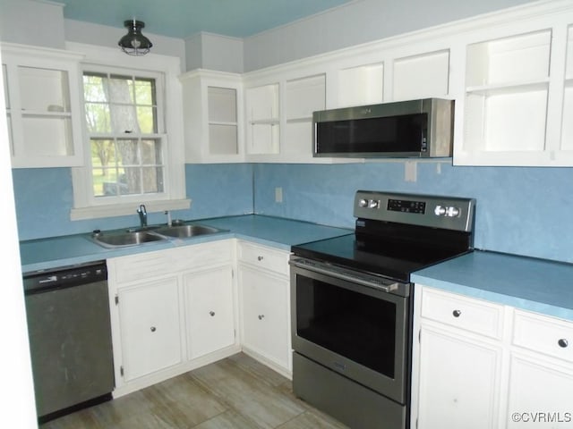 kitchen with white cabinets, backsplash, light countertops, a sink, and appliances with stainless steel finishes