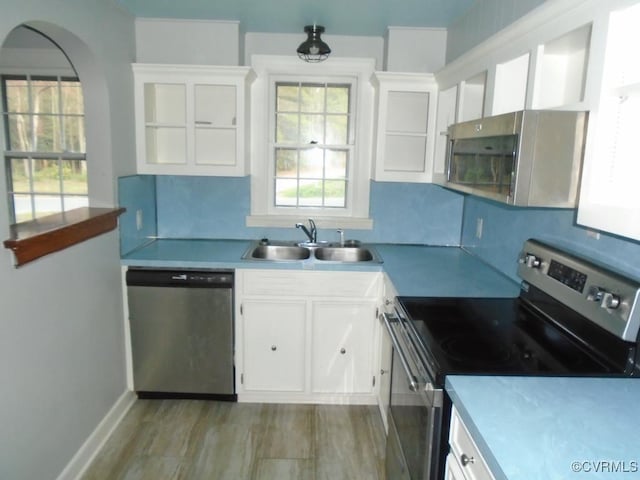 kitchen featuring stainless steel appliances, light countertops, a sink, and white cabinetry
