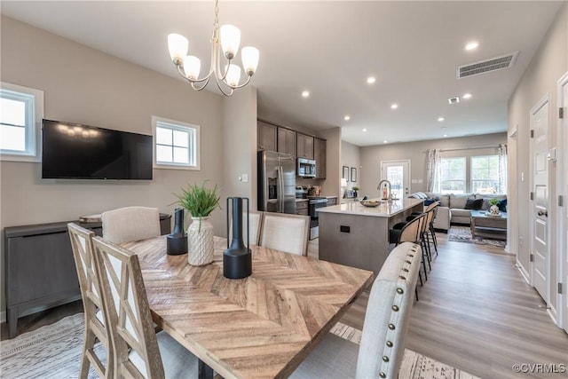 dining area with visible vents, recessed lighting, light wood finished floors, and an inviting chandelier