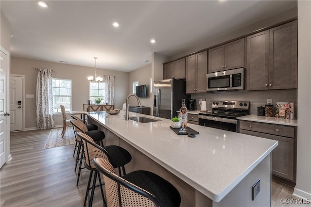 kitchen featuring appliances with stainless steel finishes, a sink, light countertops, a notable chandelier, and recessed lighting