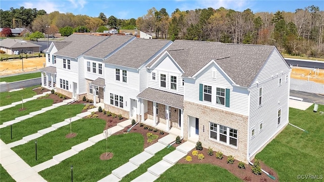 view of front of house featuring a shingled roof, stone siding, and a front lawn