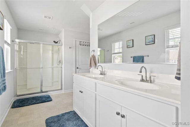 bathroom with a stall shower, double vanity, and baseboards