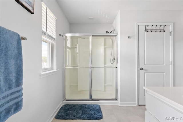 full bathroom with a stall shower, baseboards, and vanity