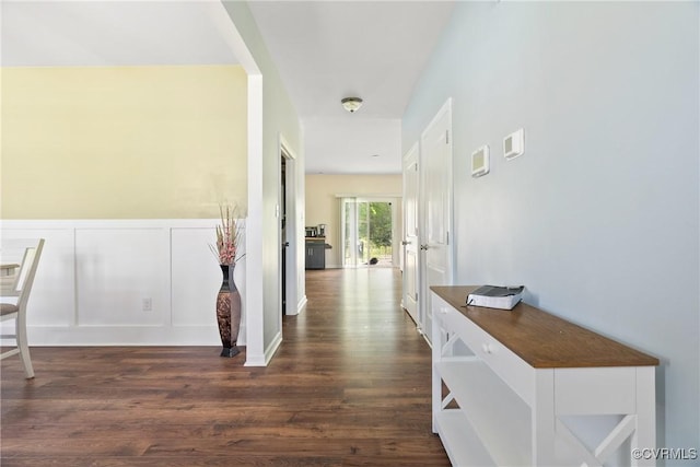 corridor with dark wood-style floors and a decorative wall