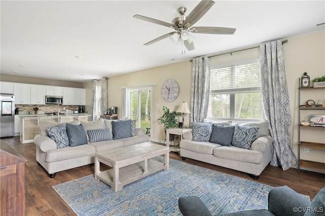 living room featuring healthy amount of natural light, ceiling fan, and dark wood-type flooring