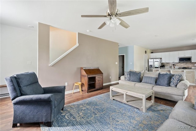 living room with ceiling fan, light wood finished floors, and baseboards