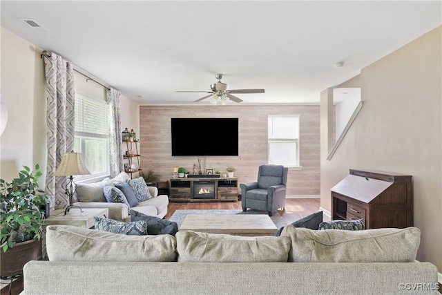 living room with a ceiling fan, plenty of natural light, wood finished floors, and a glass covered fireplace