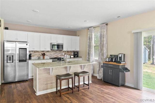 kitchen with stainless steel appliances, white cabinetry, light stone counters, and decorative backsplash