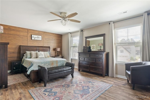 bedroom featuring wood finished floors, baseboards, wooden walls, and a ceiling fan