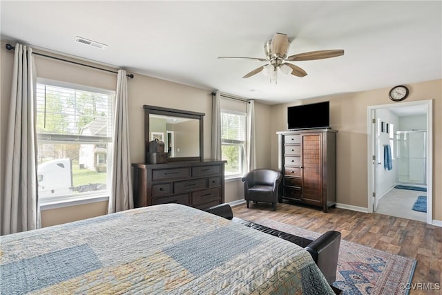 bedroom with wood finished floors, baseboards, ensuite bathroom, and ceiling fan