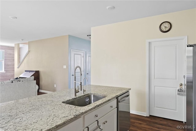 kitchen featuring a sink, stainless steel appliances, white cabinets, light stone counters, and dark wood-style floors