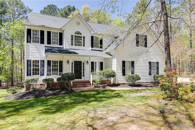 view of front of house with roof with shingles, a porch, and a front yard