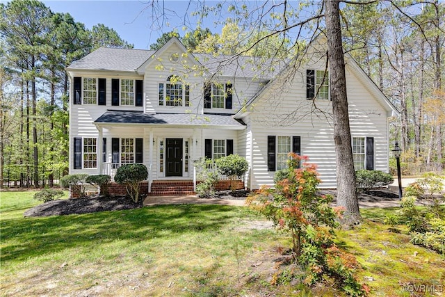 view of front of home featuring a shingled roof, a front lawn, and covered porch