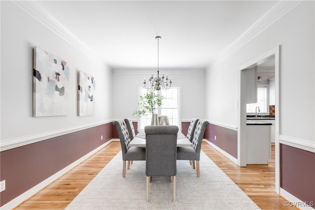 dining area with baseboards, a notable chandelier, crown molding, and light wood-type flooring