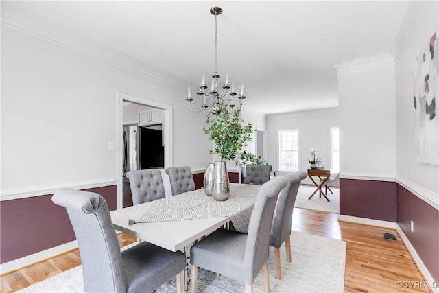 dining room with wood finished floors, ornamental molding, and an inviting chandelier