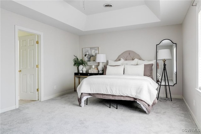 carpeted bedroom with baseboards, a tray ceiling, and visible vents