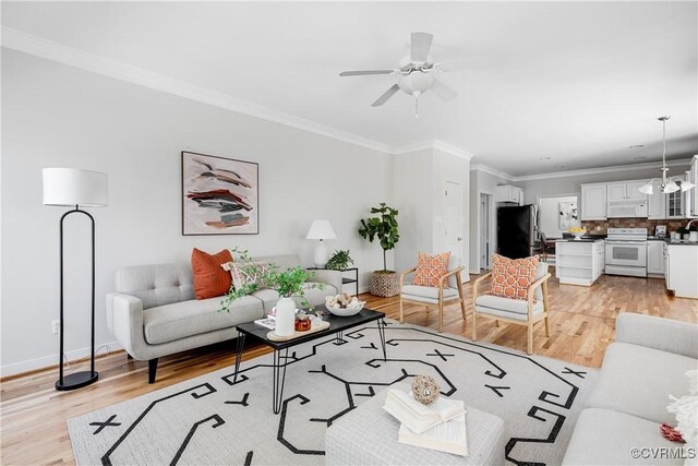 living area featuring light wood-type flooring, crown molding, baseboards, and a ceiling fan