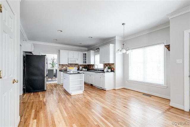 kitchen featuring white cabinets, dark countertops, visible vents, a sink, and white appliances