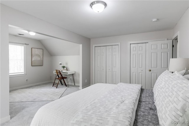 bedroom featuring light carpet, multiple closets, and baseboards