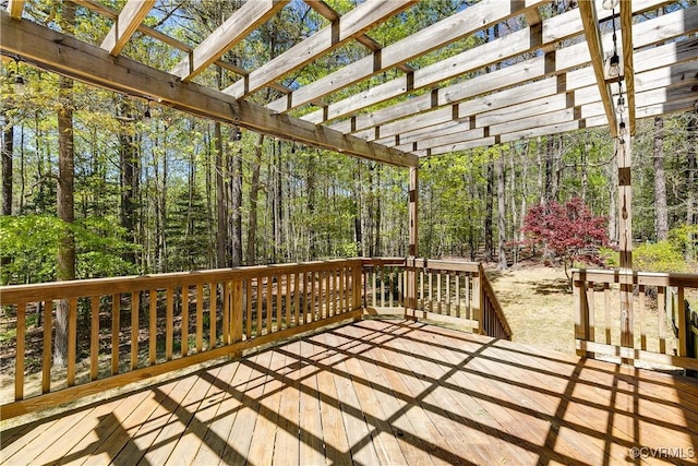 wooden terrace featuring a forest view and a pergola